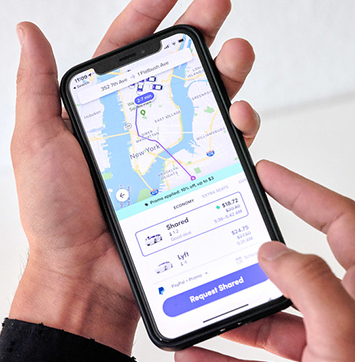 Image of person holding smartphone using Lyft app.