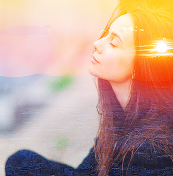 Close up image of woman meditating outdoors with eyes closed, combined photograph of nature, sunrise or sunset.
