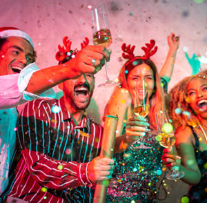 Image of friends having fun at New Year party, dancing, singing, throwing confetti and making a toast while drinking.
