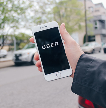 Image of hand holding smartphone with Uber logo on screen.
