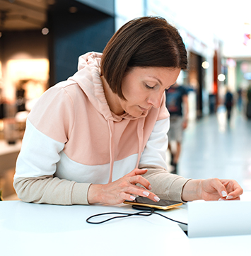 Image of woman holding smartphone while charging in a public place.