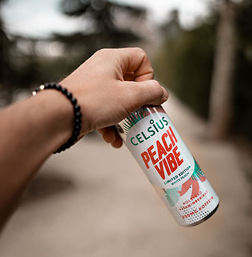 Image of hand holding Celsius Peach Vibe bottle.