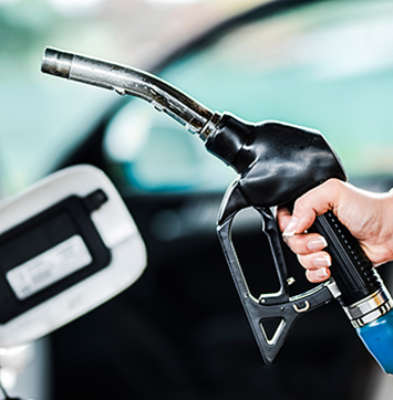 Image of woman pumping petrol at gas station into vehicle.